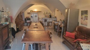 Ein geräumiges Wohnzimmer mit einem langen Holztisch, einem braunen Ledersofa und einem Fernseher auf einer Holzkommode.