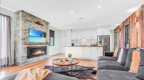 A modern living room with a stone fireplace, a flat-screen TV, and a cozy seating area.