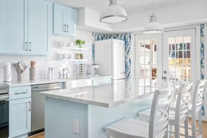 A modern kitchen with light blue cabinets, a white island, and a refrigerator.