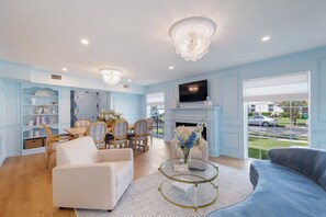 A spacious living room with a fireplace, a television, and a view of the street.