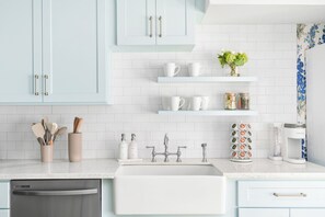A modern kitchen with light blue cabinets, white countertops, and a stainless steel dishwasher.