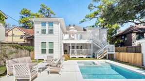 A two-story house with a balcony, a swimming pool, and outdoor furniture.