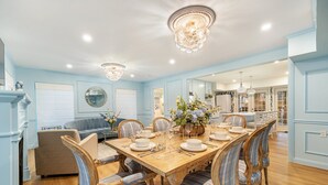 A dining room with a wooden table set for six, surrounded by six upholstered chairs with blue and white stripes.
