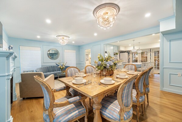 A dining room with a wooden table set for six, surrounded by six upholstered chairs with blue and white stripes.