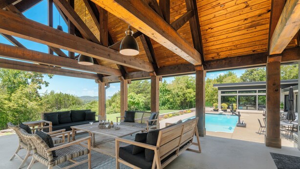 Une terrasse extérieure avec des meubles en bois, une piscine et une vue sur la végétation environnante.