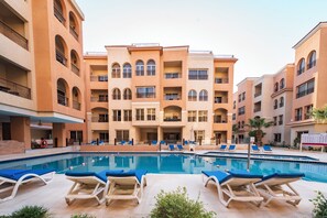 A hotel with a swimming pool surrounded by lounge chairs, multiple balconies, and a consistent architectural style. - La Rosa Boho Aquapark Hotel (Hurghada)