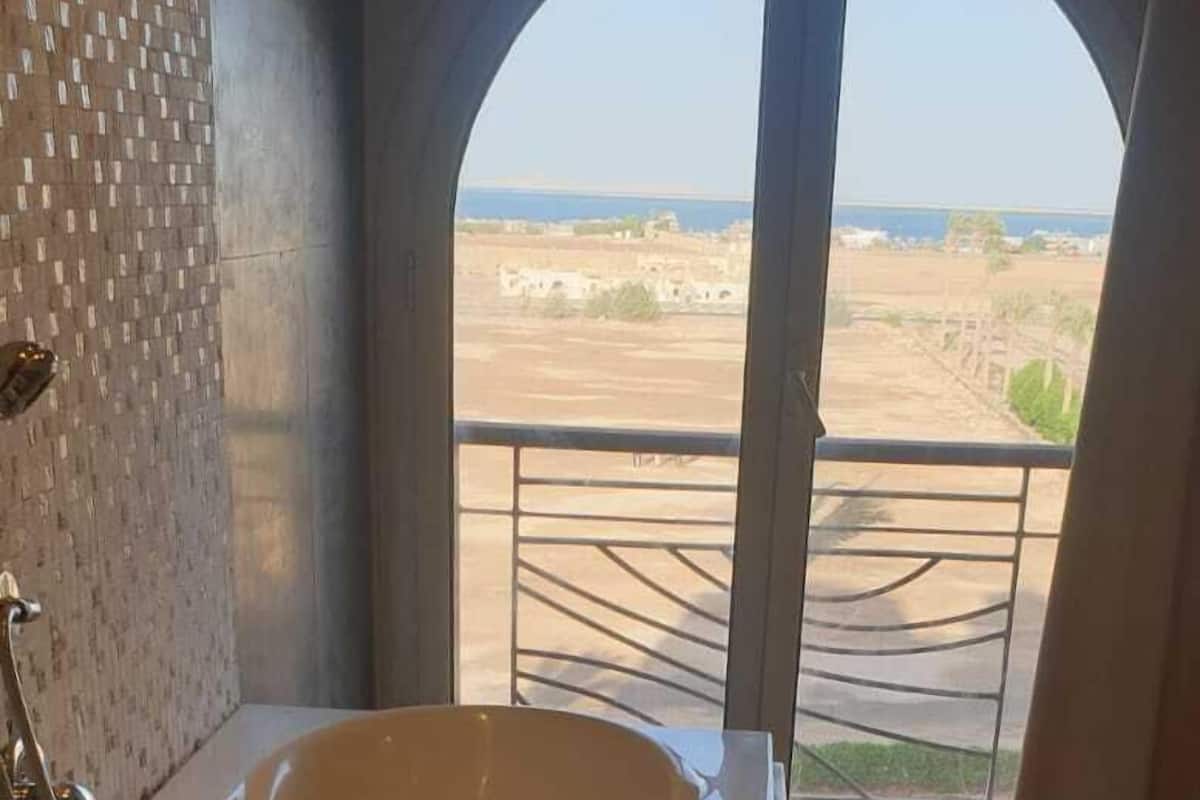 Una bañera grande en una habitación con vistas a un paisaje lejano a través de un amplio ventanal arqueado.