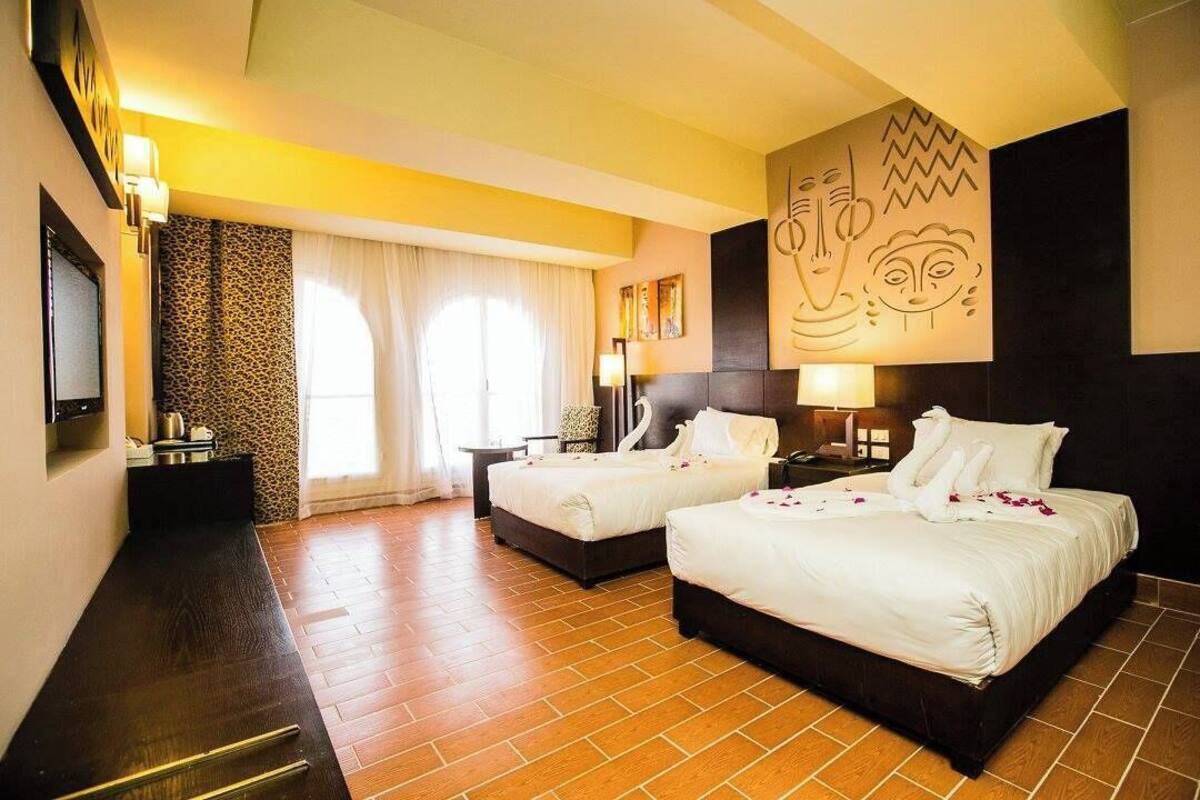 Habitación de hotel con dos camas, un mural grande en la pared y suelo de madera.