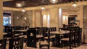 Ein Restaurant mit Marmorwänden, Holzsesseln und hängenden Pendelleuchten.