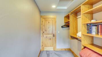 A hallway with a wooden door, a bookshelf with books, and a grey carpet.