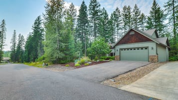 A two-story house with a garage, surrounded by a forest.