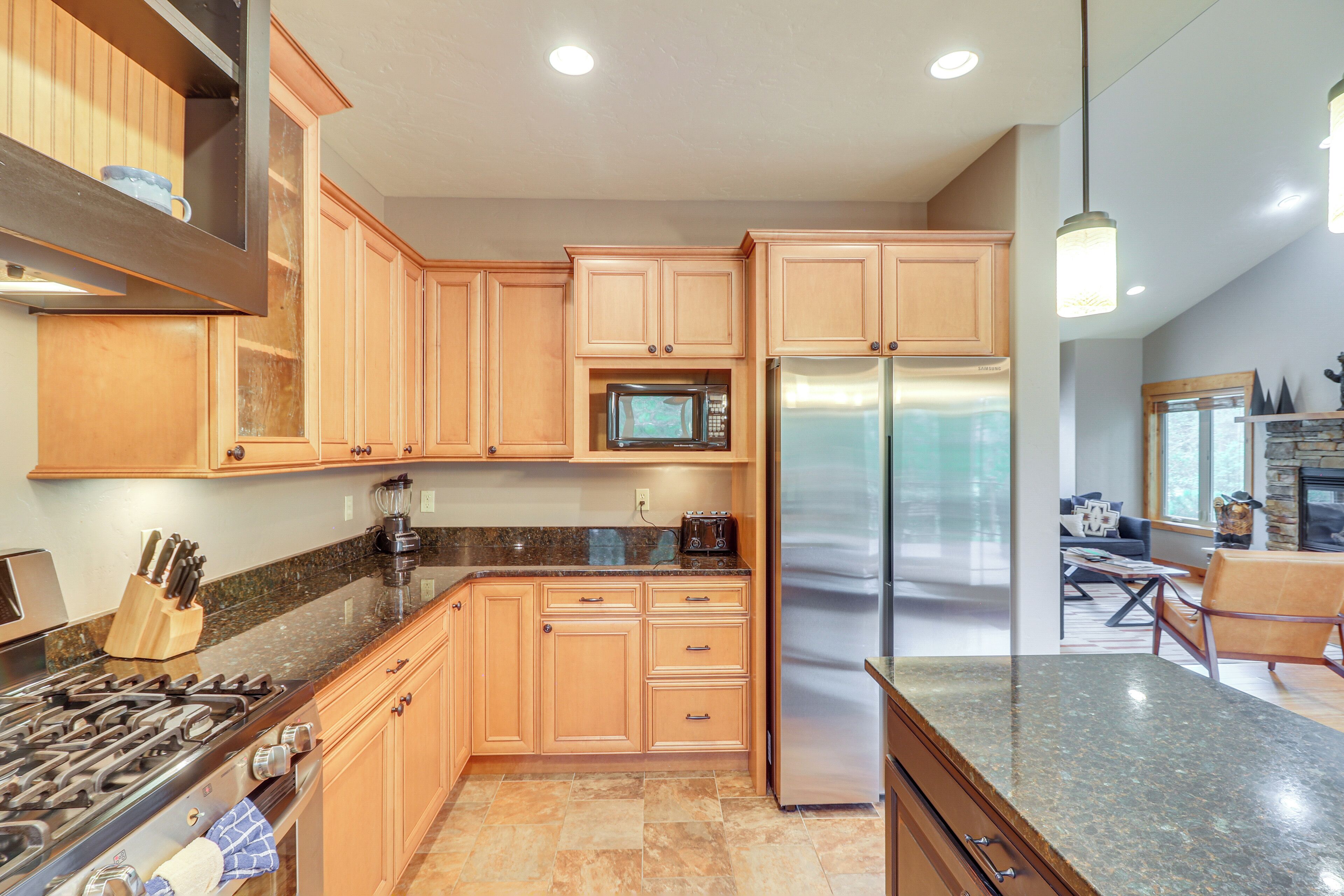 A modern kitchen with wooden cabinets, stainless steel appliances, and a granite countertop.
