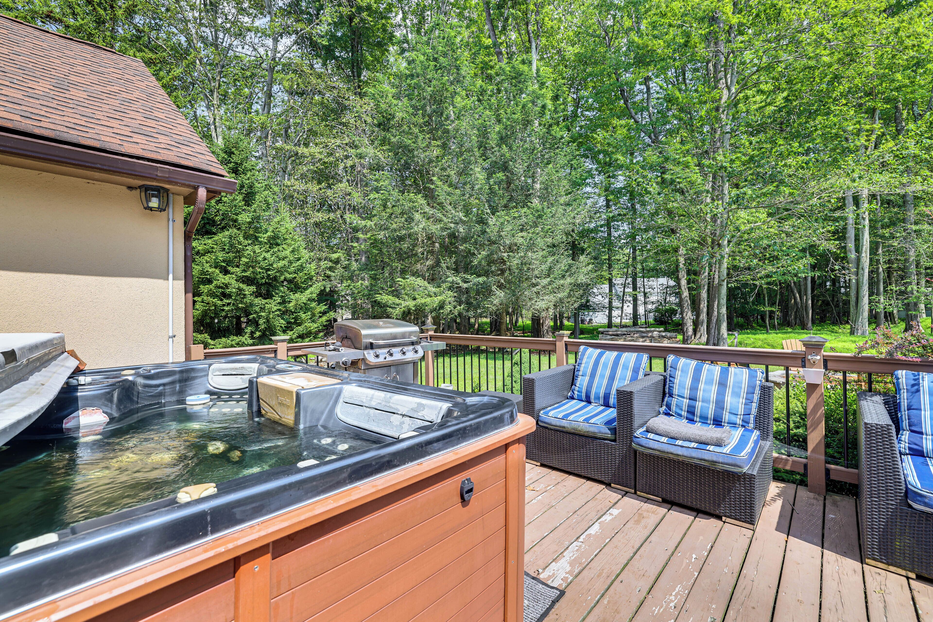 A deck with a hot tub, outdoor furniture, and a barbecue grill.