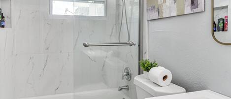 Ein modernes Badezimmer mit einer einteiligen Duschkabine, einer Toilette und einem Waschbecken.