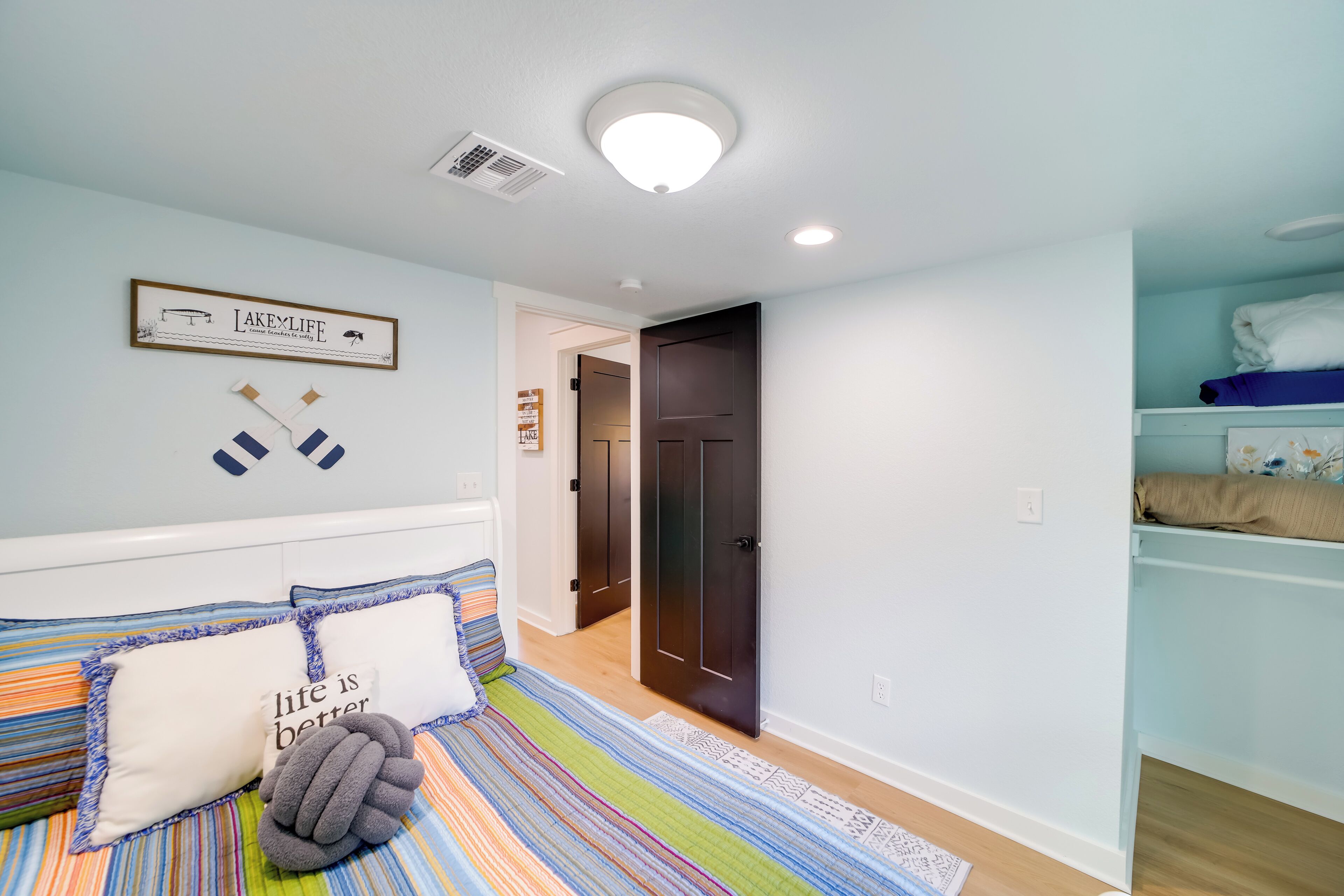 Un dormitorio con cama, almohadas, un cuadro enmarco y una puerta que da a otra habitación.
