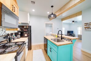 A modern kitchen with a central island, wooden cabinets, and a black refrigerator. - Eufaula Vacation Rental: Walk to Lakeside Beaches! (Eufaula)