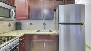 A kitchen with dark wooden cabinets, a stainless steel refrigerator, a microwave, a coffee maker, and a sink. - 2 Mi to Ocean: Dog-friendly Hallandale Beach Condo (Hallandale Beach)