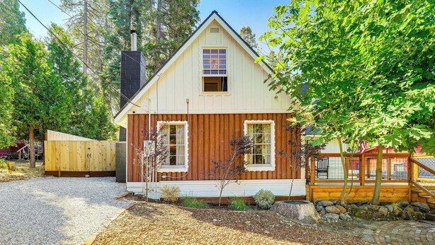 Une petite maison à un étage, avec un toit en pente, une cheminée et un porche à l’avant.