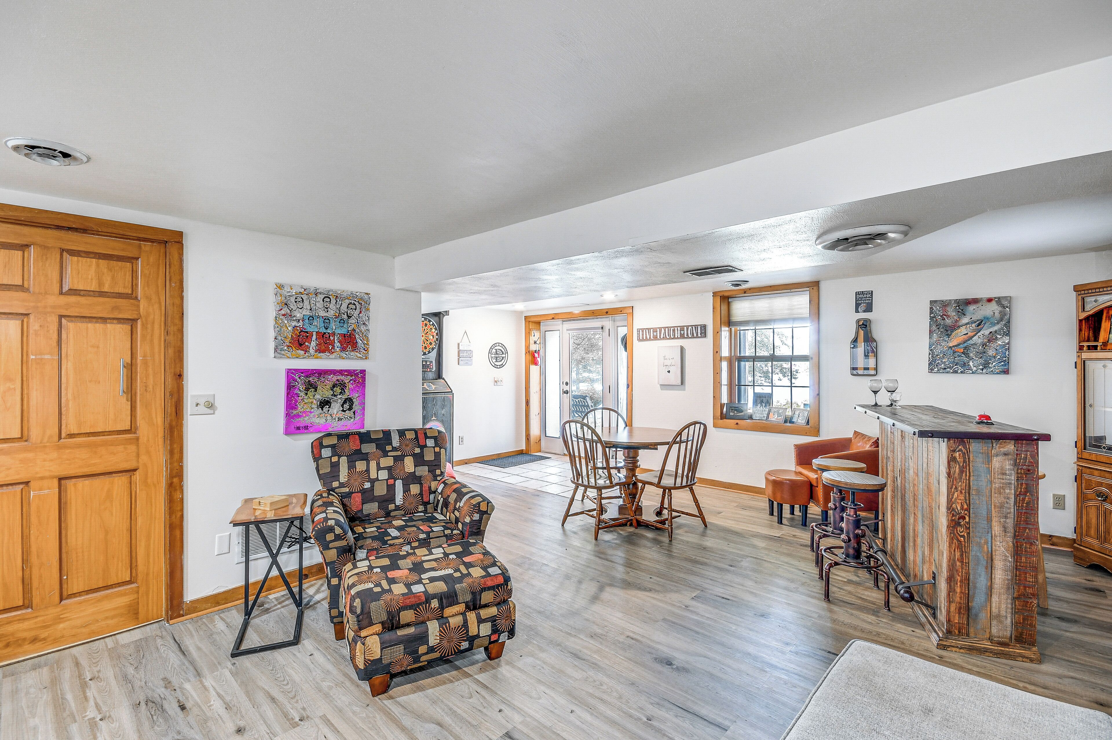 Un amplio espacio habitable con un piso de madera, un sillón estampado, una mesa de comedor con sillas y una zona de bar.