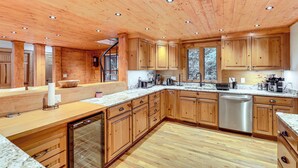 A spacious kitchen with wooden cabinets, a stainless steel dishwasher, and a marble countertop. - Luxe Smoky Mountains Cabin w/ Hot Tub & Views! (Waynesville)
