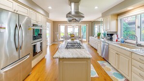 A spacious kitchen with a central island, stainless steel appliances, and a large window providing natural light. - Luxury Waterfront Home in Chesterfield w/ Views! (New Baltimore)
