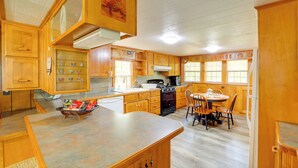 A spacious kitchen with wooden cabinets, a central island, and a dining area with chairs.