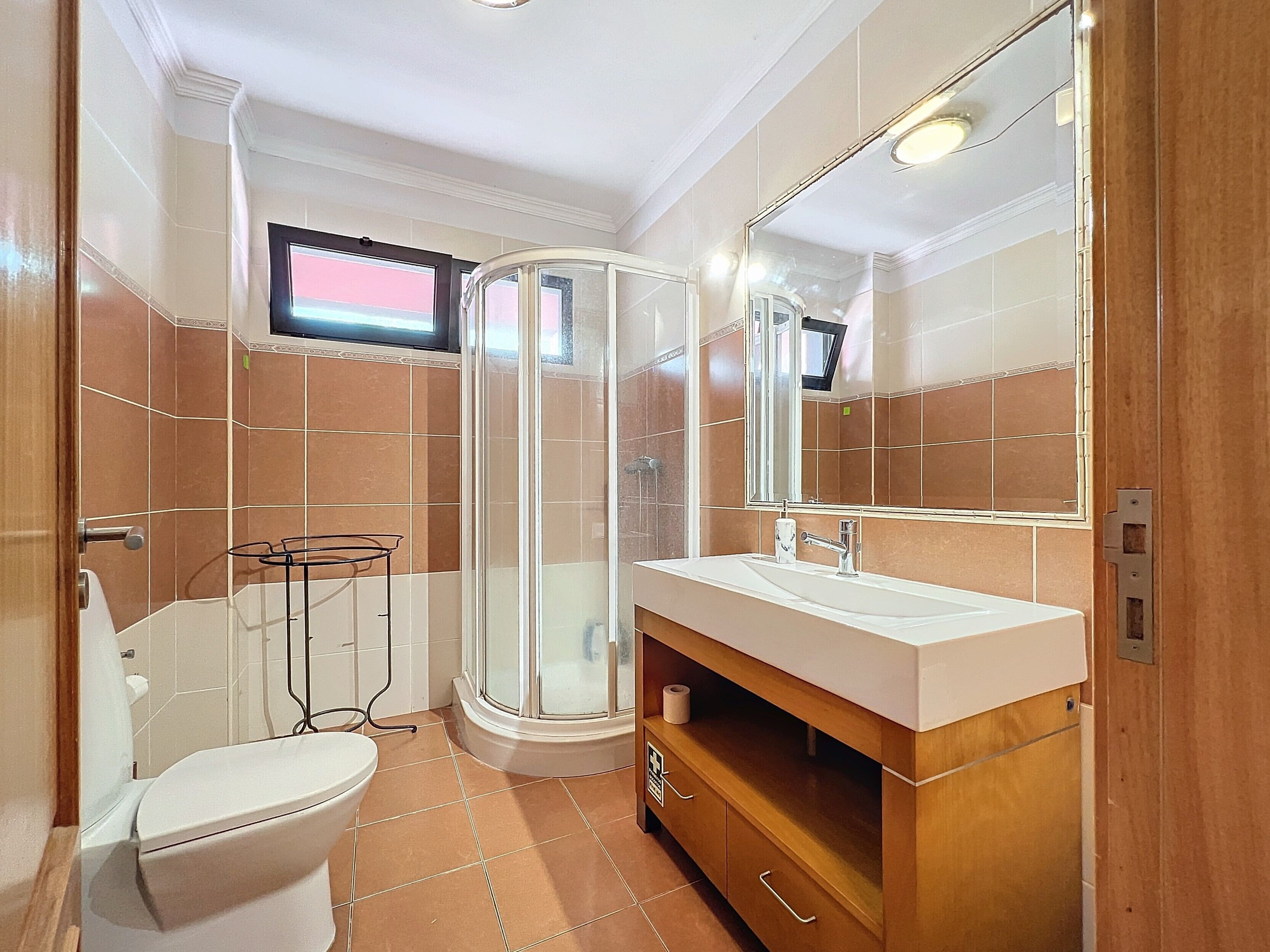 Uma casa de banho moderna com sanita, lavatório e chuveiro.