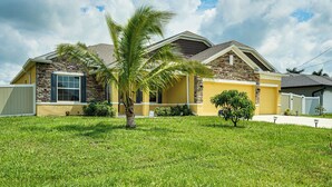 A two-story house with a stone facade, a yellow exterior, and a well-maintained lawn. - 4 Mi to Golf: Gem w/ Pool & Lanai in Cape Coral (Cape Coral)
