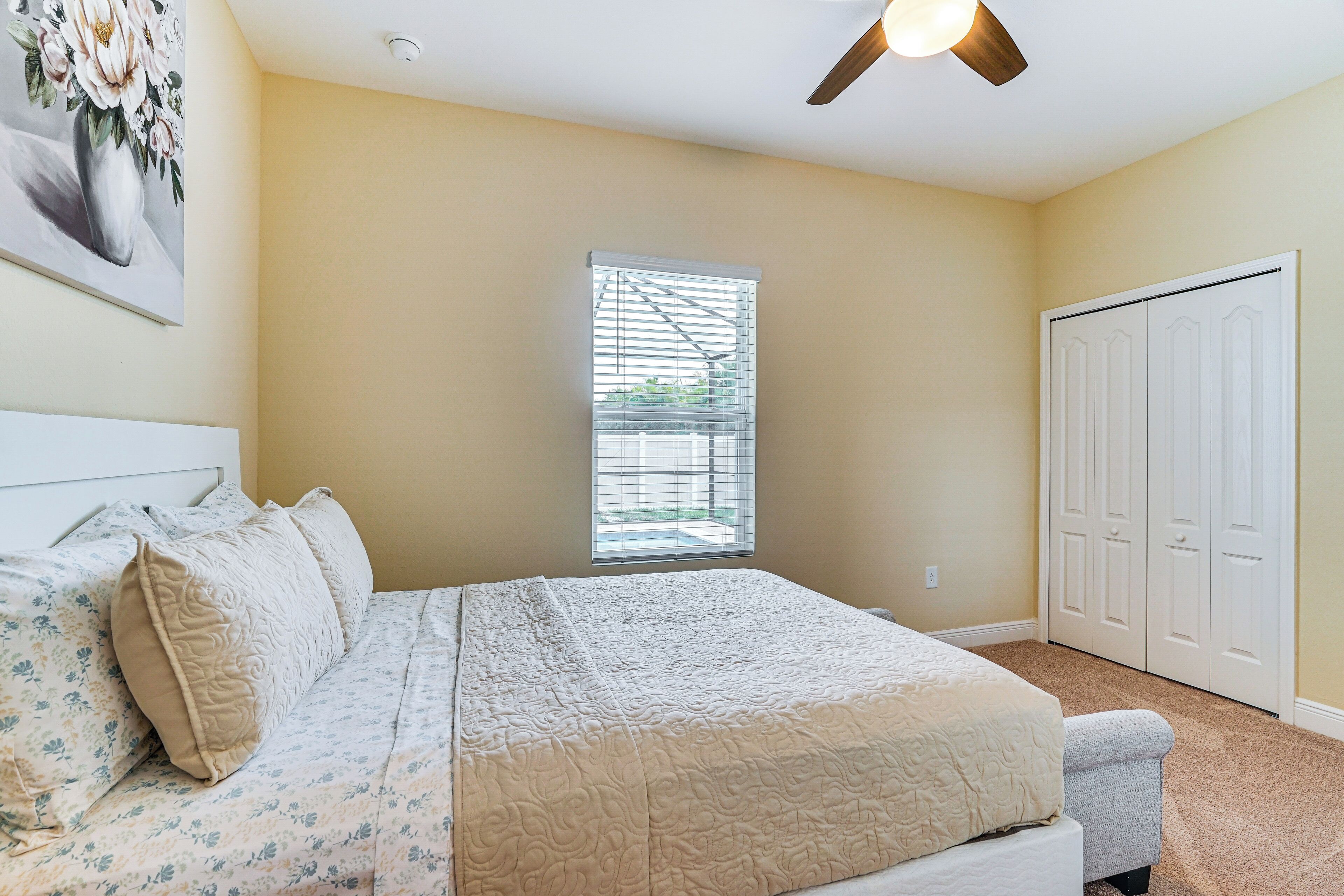 A bedroom with a bed, a ceiling fan, a window with blinds, and a closet.