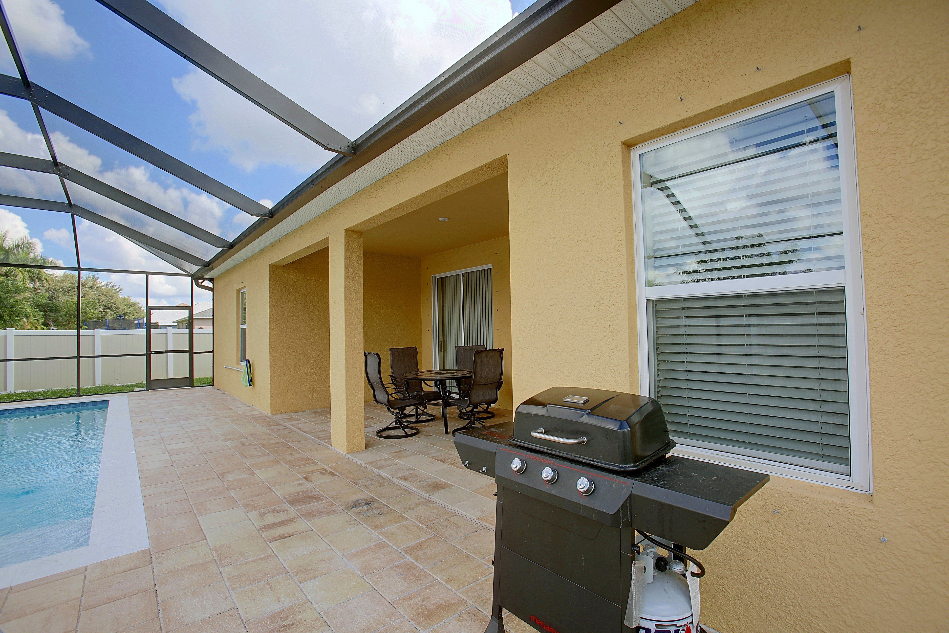 Un patio exterior con piscina, una parrilla y un comedor con sillas y una mesa.