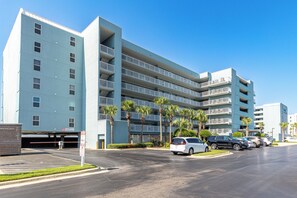 A multi-story hotel with a parking lot and several parked cars. - Islander Beach Resort 302 Gulf Front Studio (Fort Walton Beach)