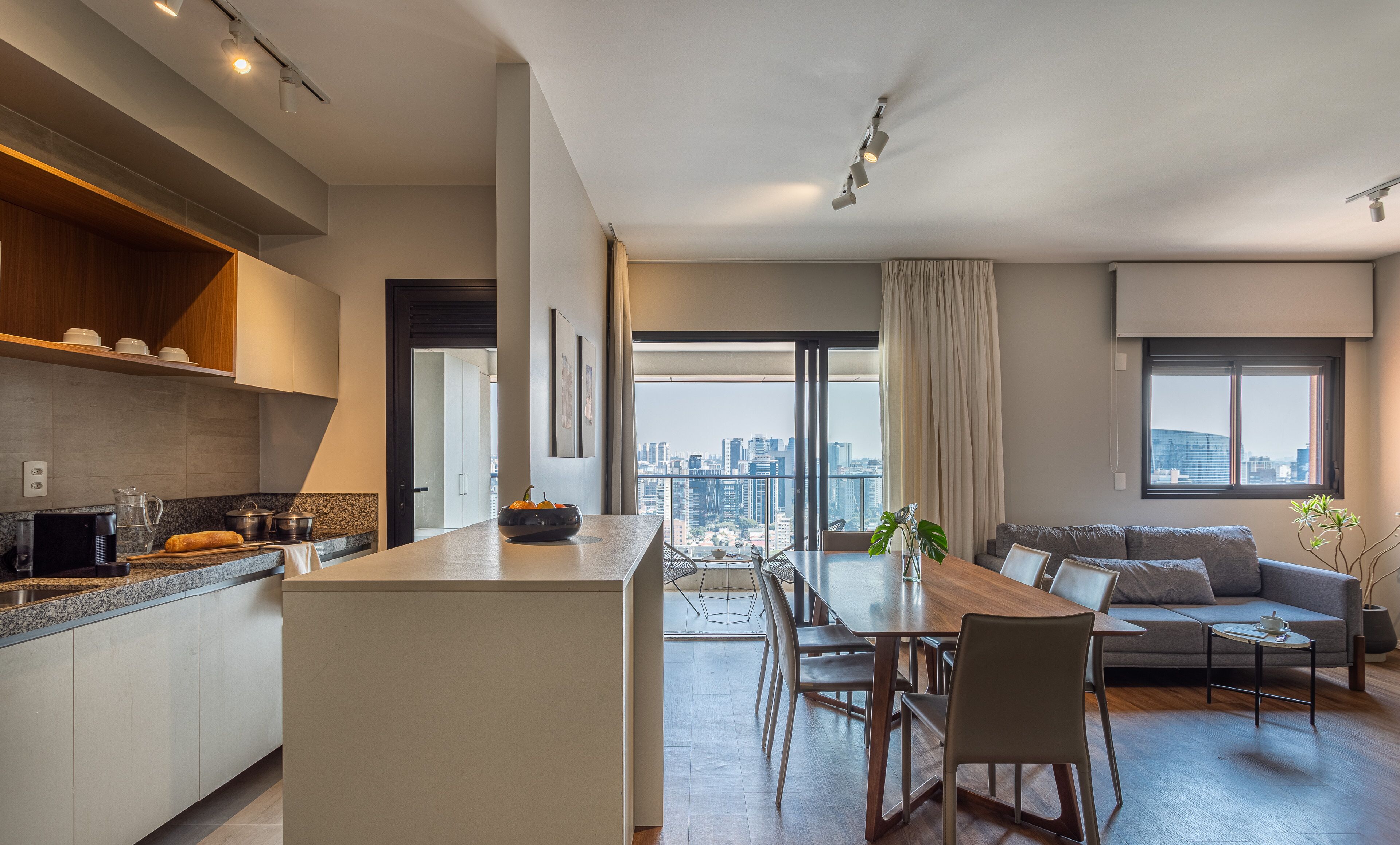 A modern apartment with a kitchen, dining area, and a living room with a city view.
