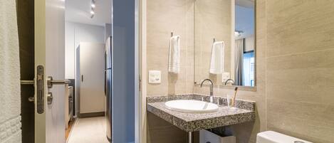 A modern bathroom with a granite countertop sink, a mirror, and a toilet.