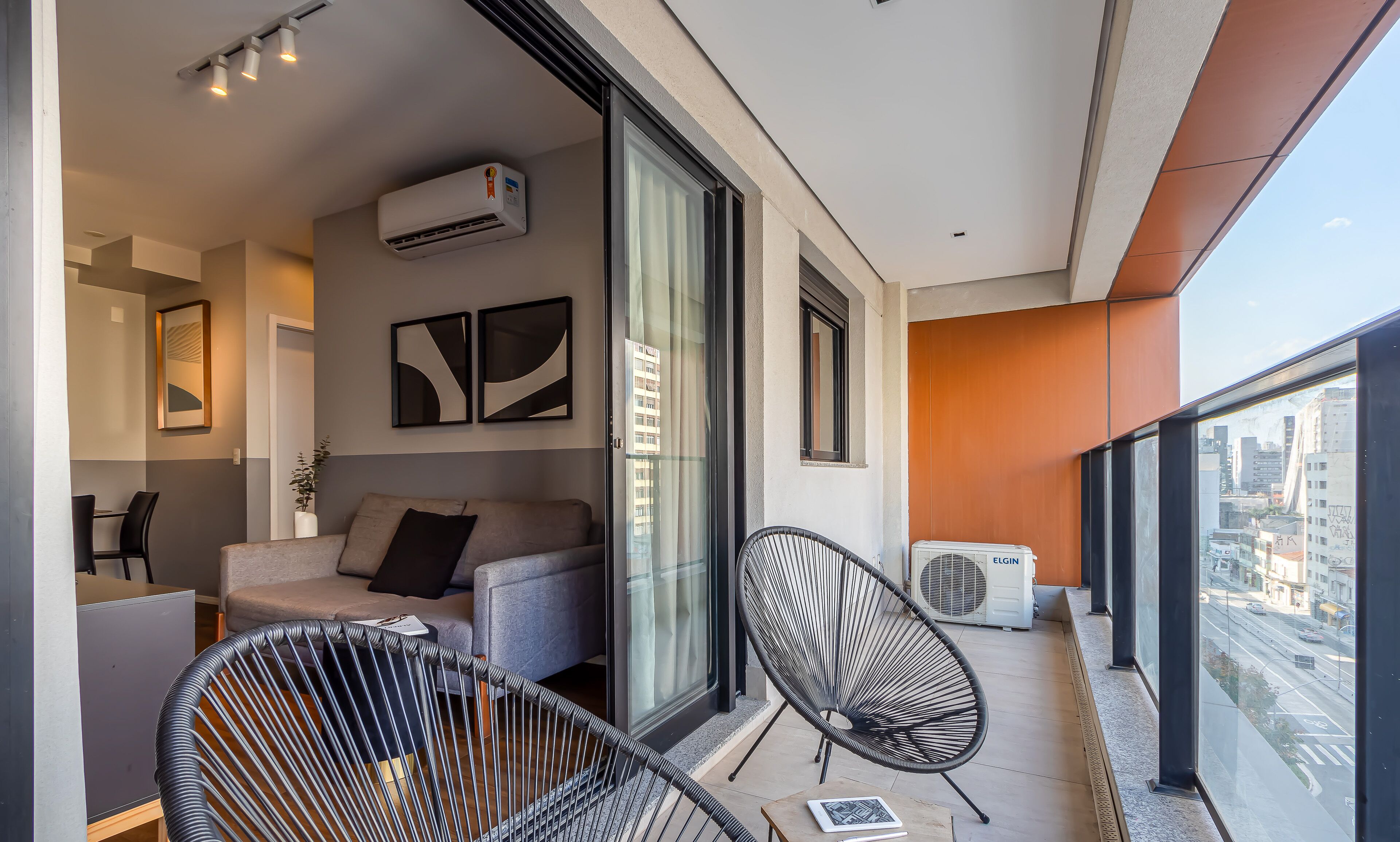 A modern balcony with a sofa, chairs, and an air conditioning unit.
