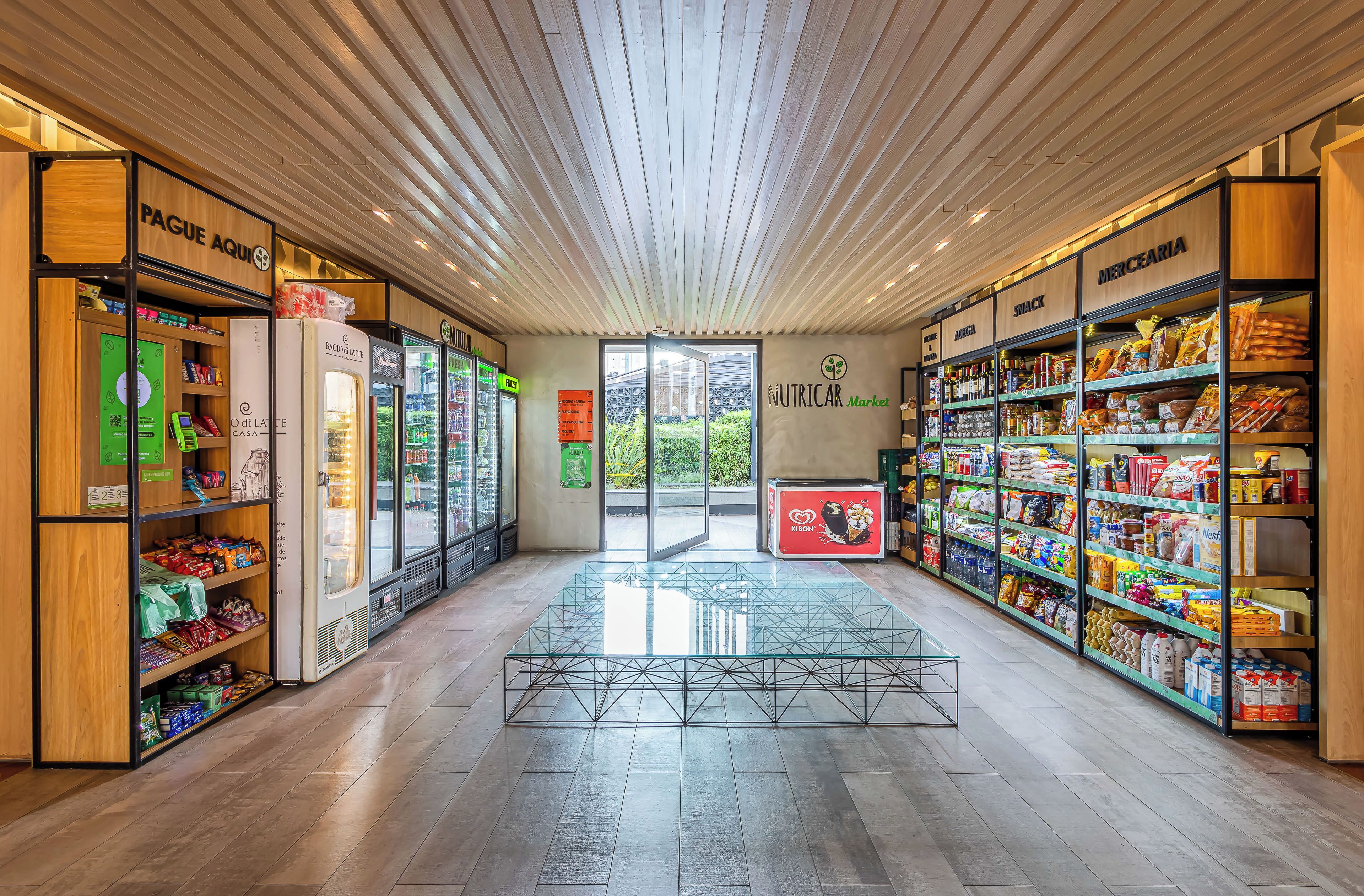 A grocery store interior with wooden flooring, glass display tables, and shelves stocked with various products.