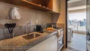 A modern kitchen with granite countertops, a built-in oven, and a view of the city through a large window.