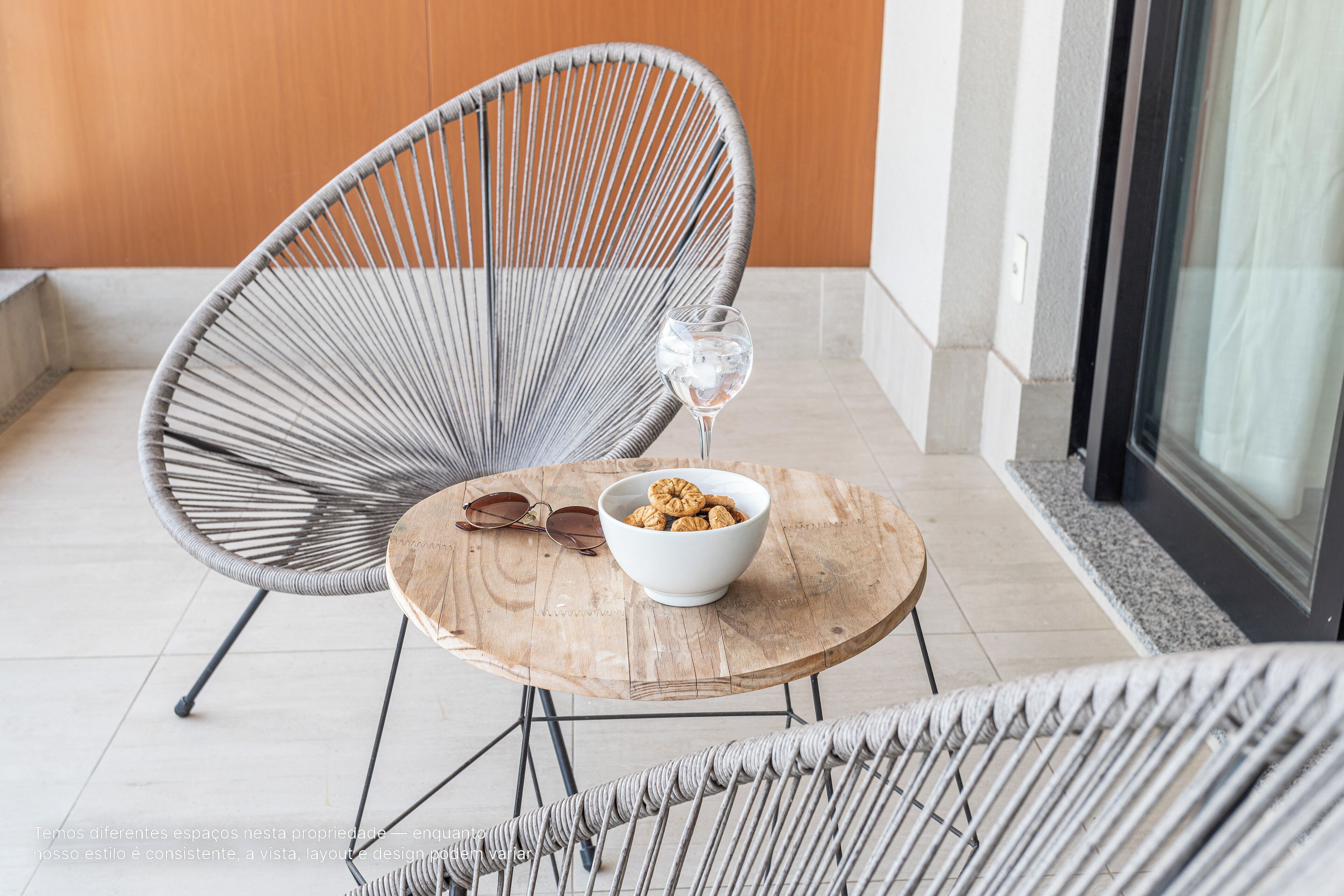A modern lounge area with wicker chairs, a wooden table, and a bowl of snacks.