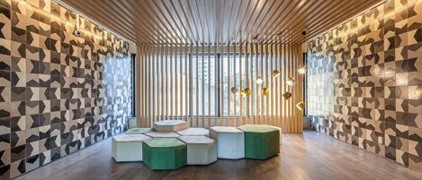 Un intérieur moderne avec des murs aux motifs géométriques, un plafond à lattes de bois et des sièges hexagonaux.