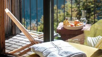 Un balcón con vistas a un área boscosa y una mesa con una toalla y fruta.