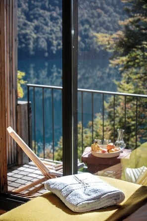 A balcony with a view of a forested area and a table with a towel and fruit. - Hermoso Eco Lodge (San Martín de los Andes)