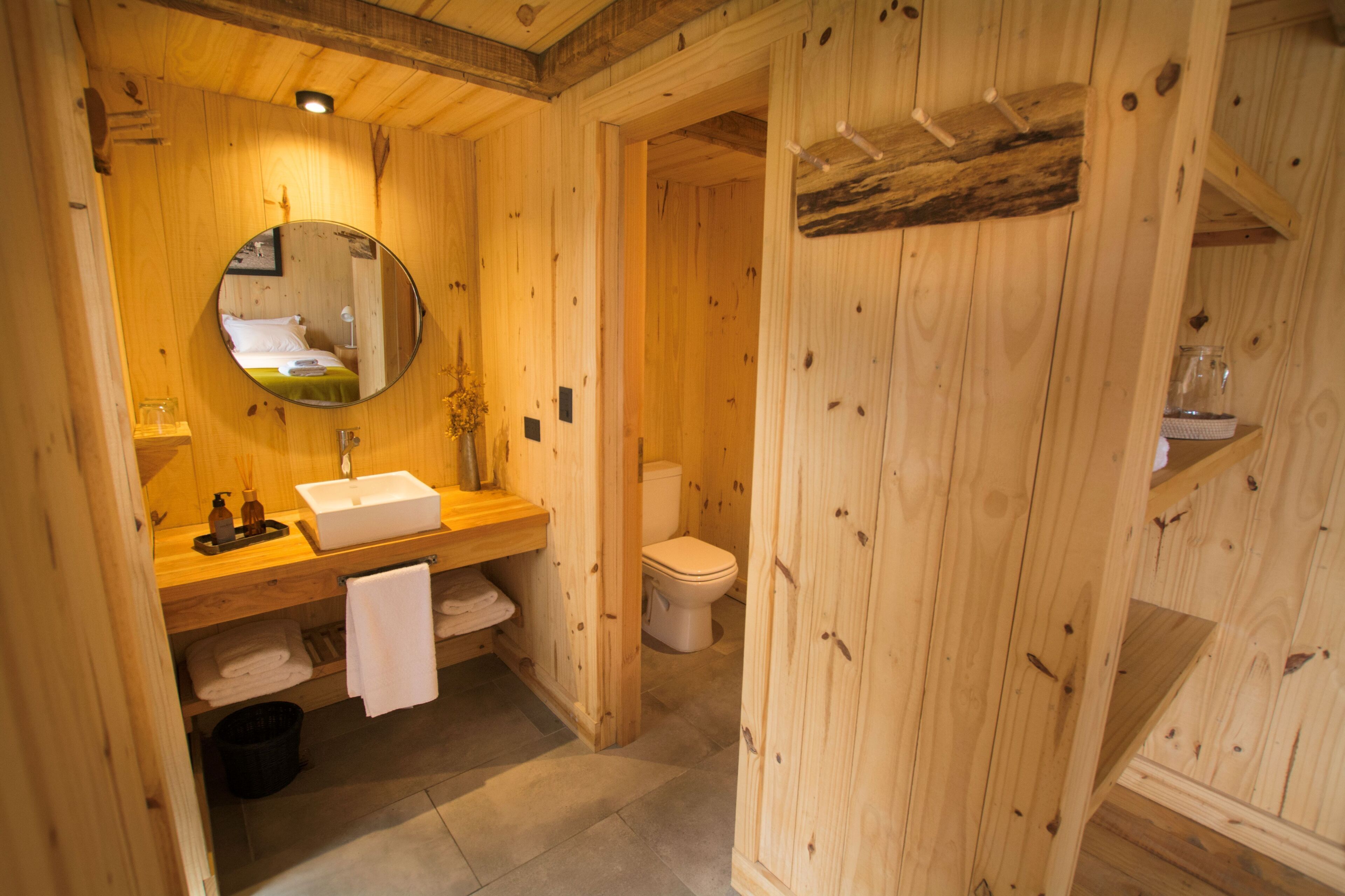 Un baño de madera con lavamanos, espejo y retrete.