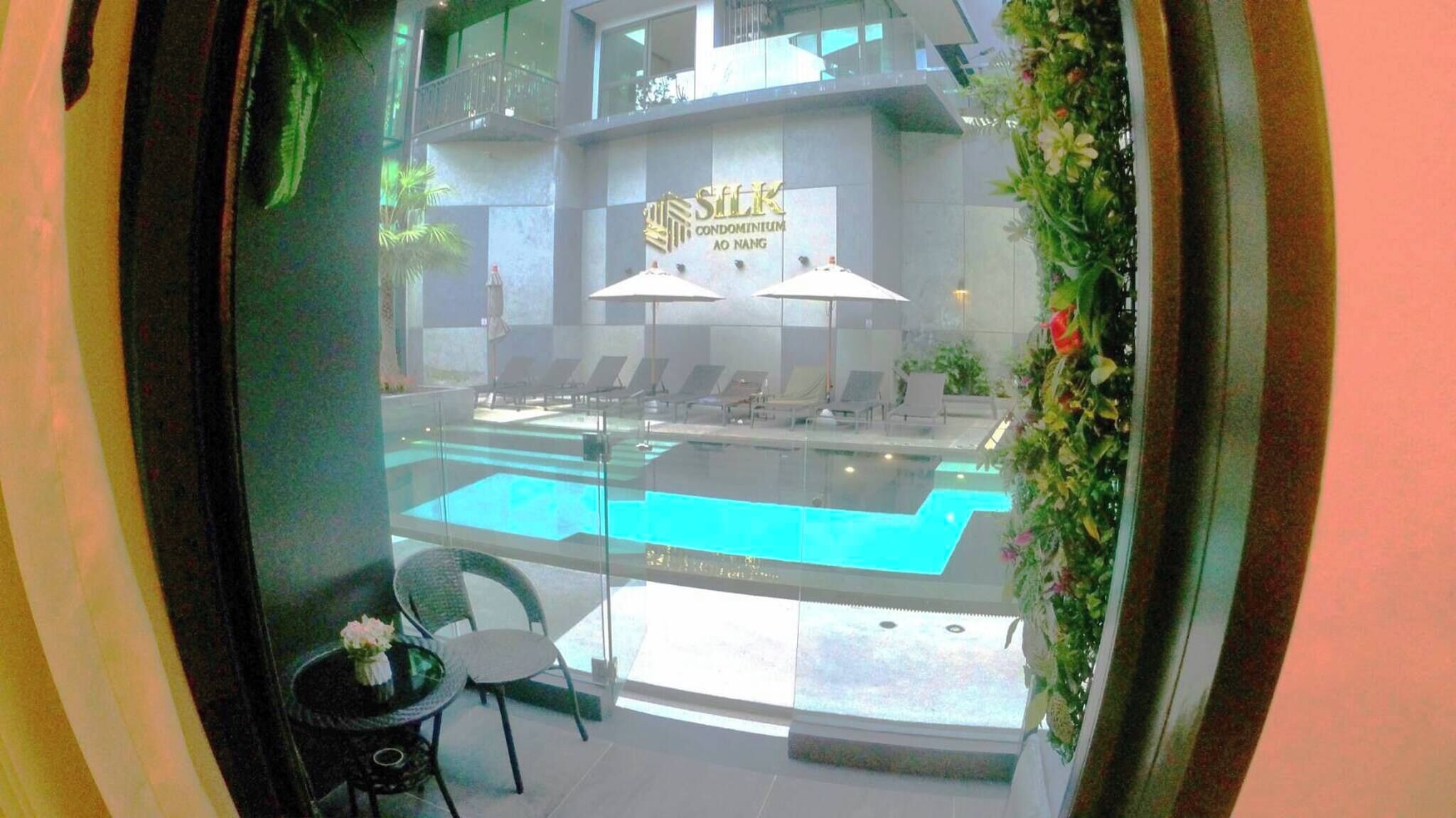 Vue d’une piscine avec des chaises longues et un panneau indiquant « Silk Condominium AO Nang ».