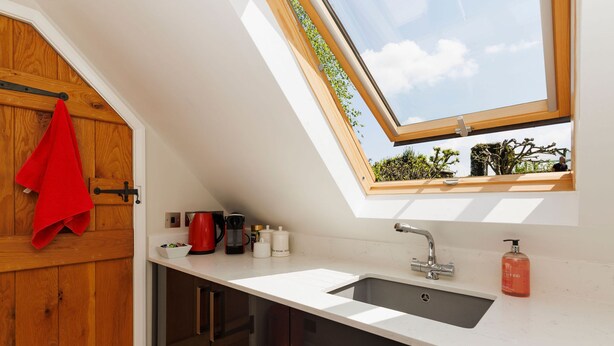 Una cocina moderna con tragaluz, un lavabo y una toalla roja colgada en una puerta de madera.