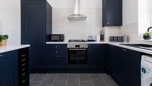 A modern kitchen with dark blue cabinets, a stainless steel range hood, a Bosch dishwasher, and a microwave. - Two bed Apartment With Sea Views in Bognor Regis (Bognor Regis)