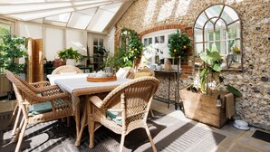 A sunlit room with a stone wall, wicker furniture, and potted plants. - Enchanting 4BD Cottage Lodge Nr Eartham Wood (Petworth)