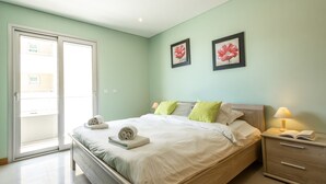 Una camera da letto con un letto, un comodino e vista attraverso una porta scorrevole.