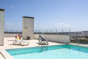 A rooftop pool with two lounge chairs, one with a colorful towel, and a clear view of the cityscape in the background. - Sunrise - Com Vista Para a Vila (Alcobaça)