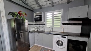 Una cocina compacta con un refrigerador de acero inoxidable, un microondas, una lavadora y un lavavajillas.