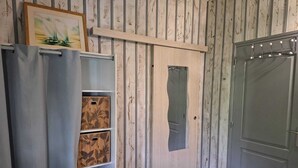 Una habitación con un armario de madera, una puerta gris y una estantería con cajas estampadas.