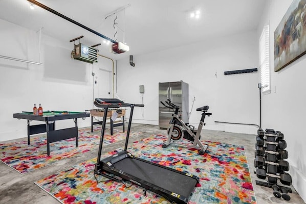 A room with a treadmill, exercise bike, and dumbbells.